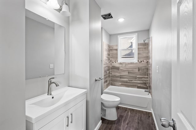 full bathroom featuring hardwood / wood-style flooring, tiled shower / bath combo, toilet, and vanity