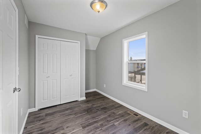 unfurnished bedroom with dark hardwood / wood-style flooring, a closet, and vaulted ceiling