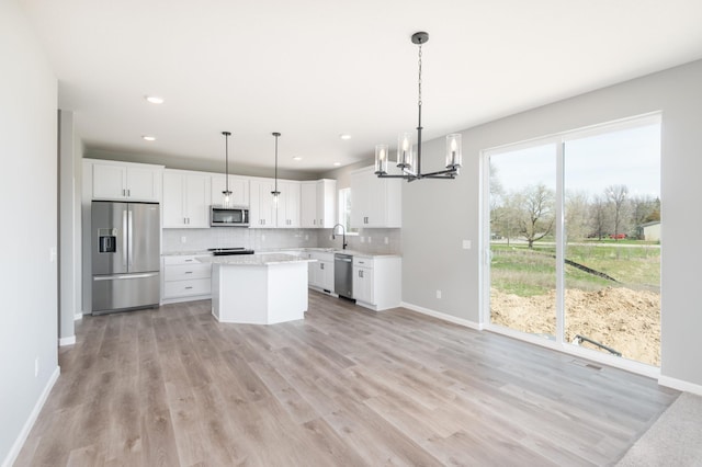 kitchen with sink, hanging light fixtures, light hardwood / wood-style floors, white cabinetry, and stainless steel appliances