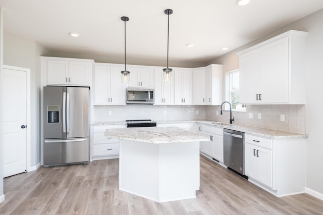 kitchen with white cabinets, decorative light fixtures, a center island, and stainless steel appliances