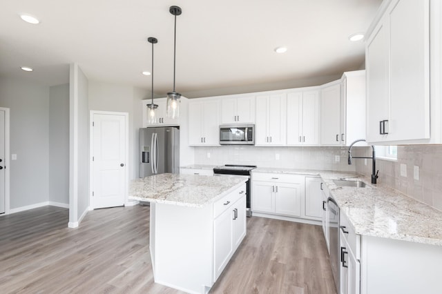 kitchen featuring sink, a center island, hanging light fixtures, white cabinets, and appliances with stainless steel finishes