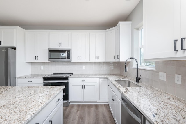 kitchen featuring white cabinetry, sink, decorative backsplash, appliances with stainless steel finishes, and light wood-type flooring