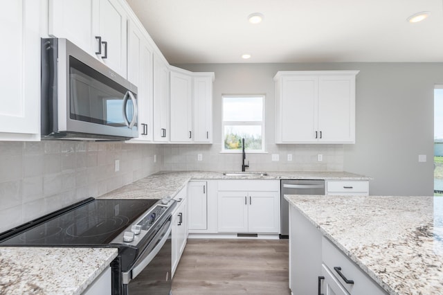 kitchen featuring white cabinets, sink, decorative backsplash, appliances with stainless steel finishes, and light hardwood / wood-style floors