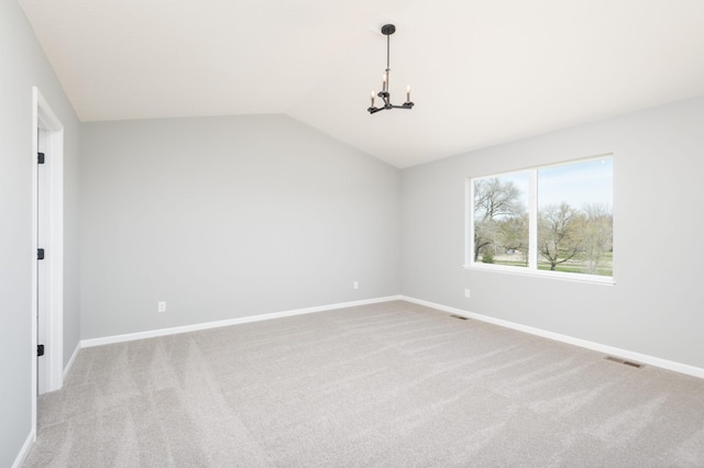 empty room featuring light colored carpet, vaulted ceiling, and a notable chandelier