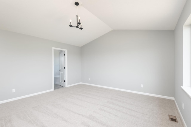 spare room featuring lofted ceiling and light carpet