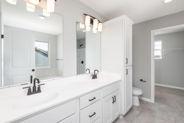 bathroom with a shower, vanity, a healthy amount of sunlight, and toilet