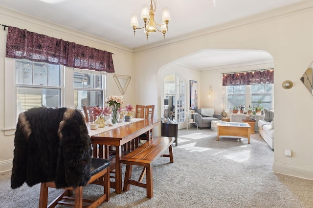 dining room featuring crown molding, carpet flooring, and an inviting chandelier