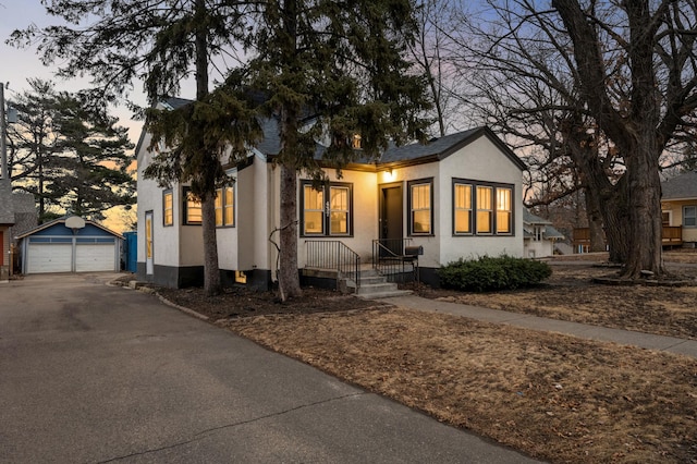 view of front of house with stucco siding, a detached garage, and an outdoor structure