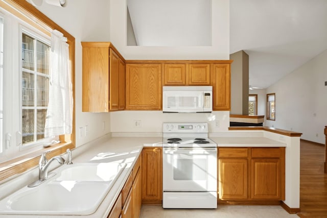 kitchen with vaulted ceiling, white appliances, kitchen peninsula, and sink