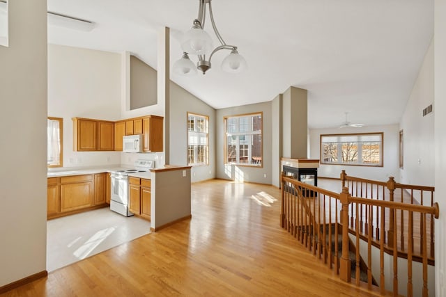 kitchen featuring white appliances, hanging light fixtures, high vaulted ceiling, light hardwood / wood-style floors, and kitchen peninsula