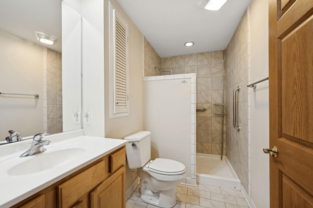 bathroom featuring vanity, a tile shower, tile patterned floors, and toilet