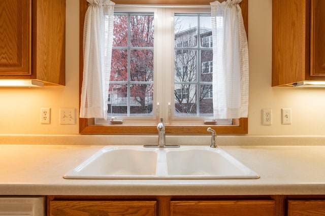 kitchen with brown cabinetry, light countertops, and a sink