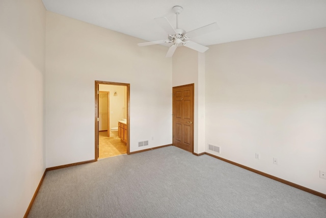 unfurnished bedroom with high vaulted ceiling, light colored carpet, visible vents, and baseboards