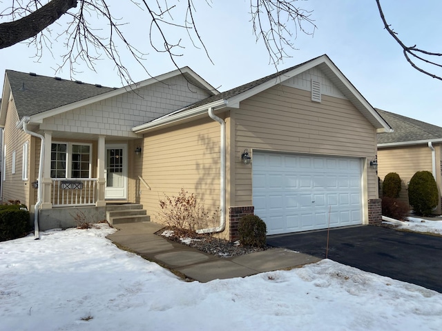 ranch-style home featuring a garage, covered porch, brick siding, and driveway