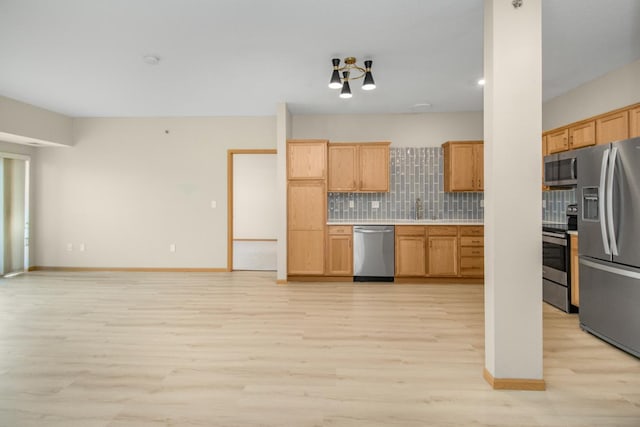 kitchen with tasteful backsplash, appliances with stainless steel finishes, and light wood-type flooring