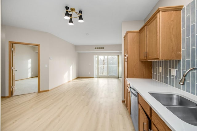 kitchen featuring sink, a chandelier, decorative backsplash, stainless steel dishwasher, and light wood-type flooring