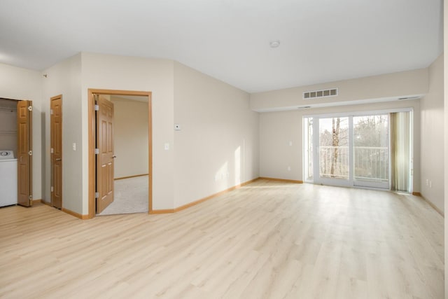 unfurnished room featuring washer / clothes dryer and light hardwood / wood-style flooring