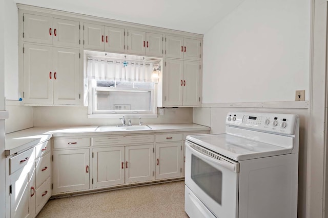 kitchen with white cabinets, light countertops, electric stove, and a sink