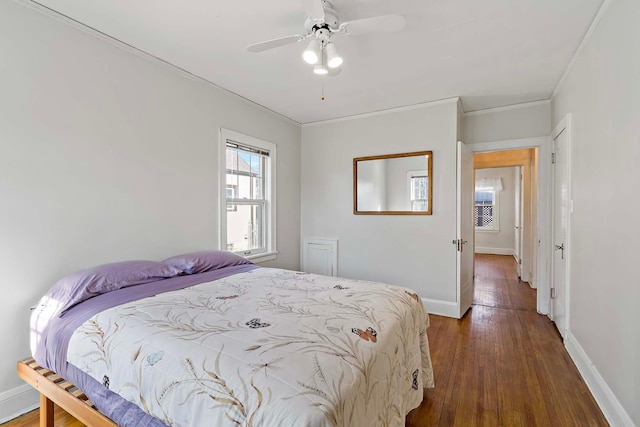 bedroom featuring dark wood-type flooring, crown molding, baseboards, and ceiling fan