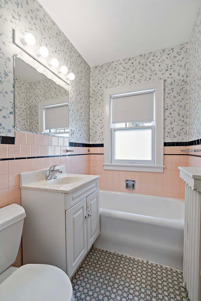 bathroom featuring vanity, toilet, wainscoting, and wallpapered walls