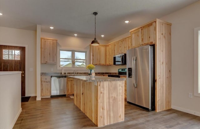 kitchen featuring pendant lighting, a center island, stainless steel appliances, light brown cabinets, and light wood-type flooring