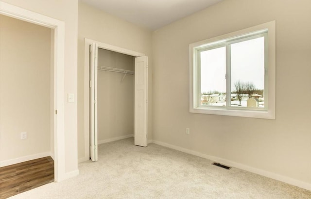 unfurnished bedroom featuring light colored carpet and a closet