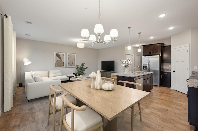 dining space featuring sink, a notable chandelier, and light wood-type flooring