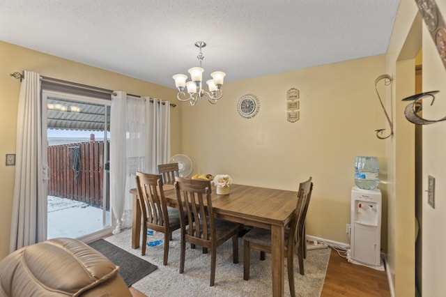 dining space with hardwood / wood-style floors, a textured ceiling, and a notable chandelier