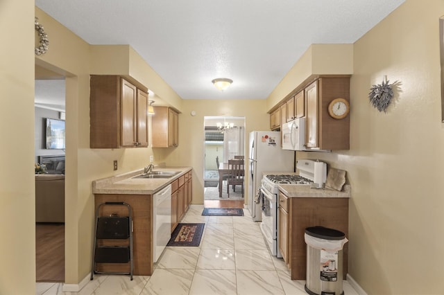 kitchen featuring sink, a chandelier, white appliances, and a textured ceiling