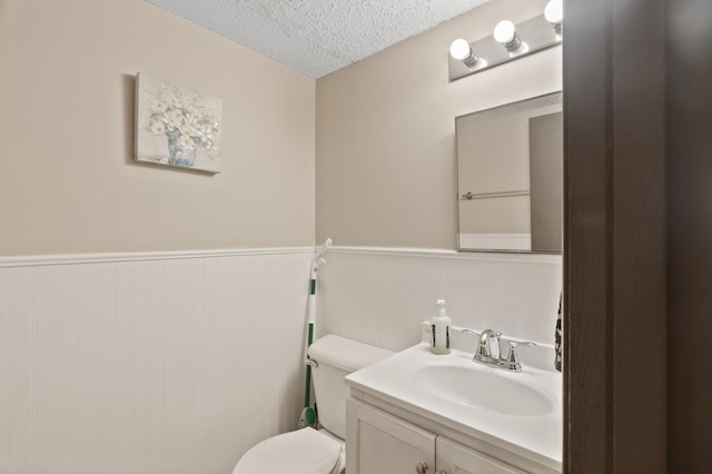 bathroom with toilet, a textured ceiling, and vanity