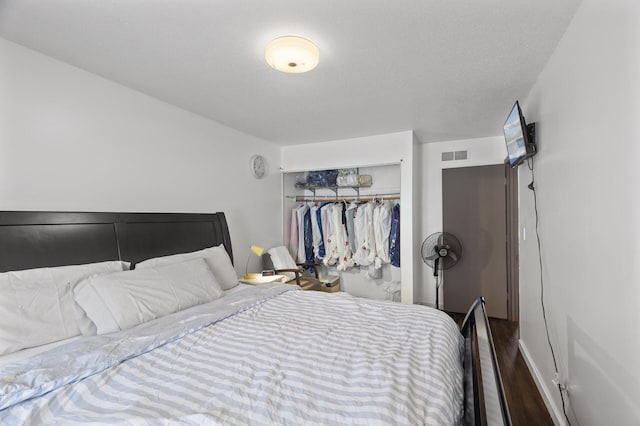 bedroom with dark hardwood / wood-style floors and a closet