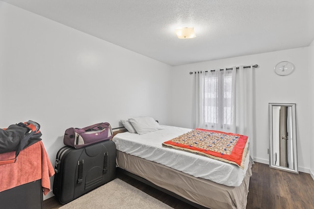 bedroom with a textured ceiling and dark hardwood / wood-style flooring