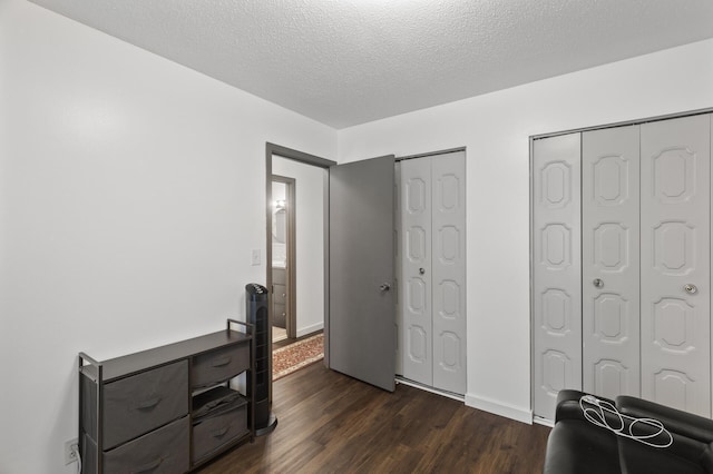 bedroom with dark hardwood / wood-style floors, a textured ceiling, and two closets