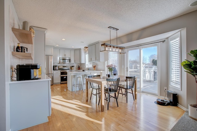 dining room with sink, a textured ceiling, and light hardwood / wood-style flooring