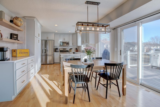 dining room with sink, a textured ceiling, and light hardwood / wood-style floors