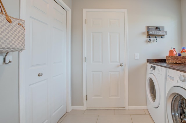 clothes washing area featuring light tile patterned flooring and washer and dryer