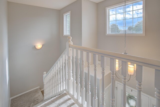 staircase with carpet floors and a notable chandelier