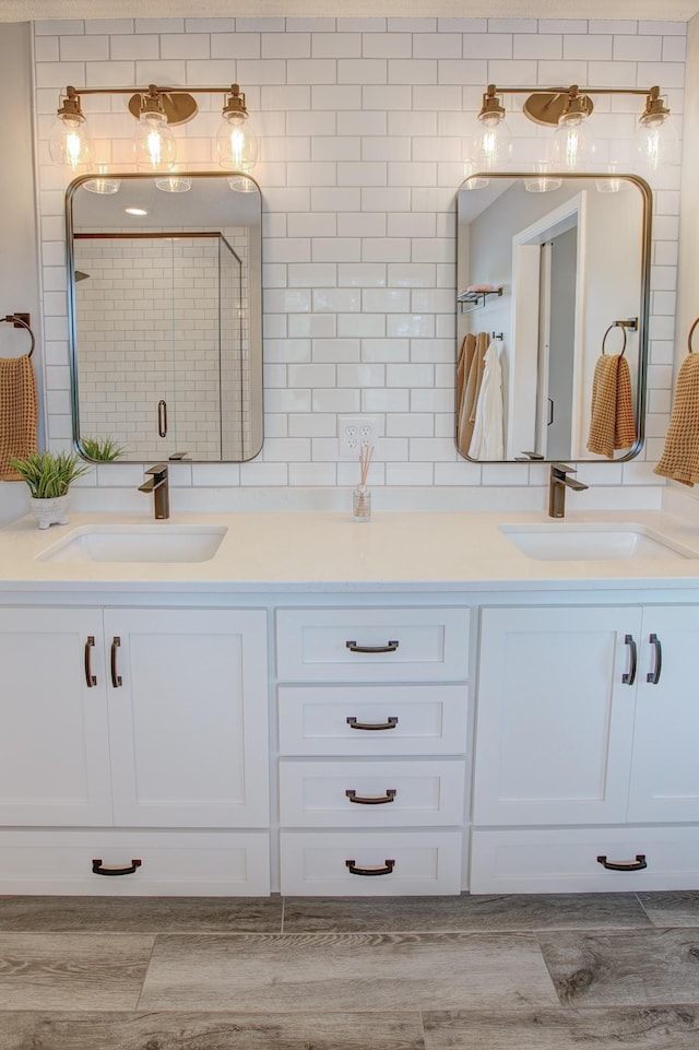 bathroom featuring hardwood / wood-style flooring, vanity, backsplash, and a shower with shower door