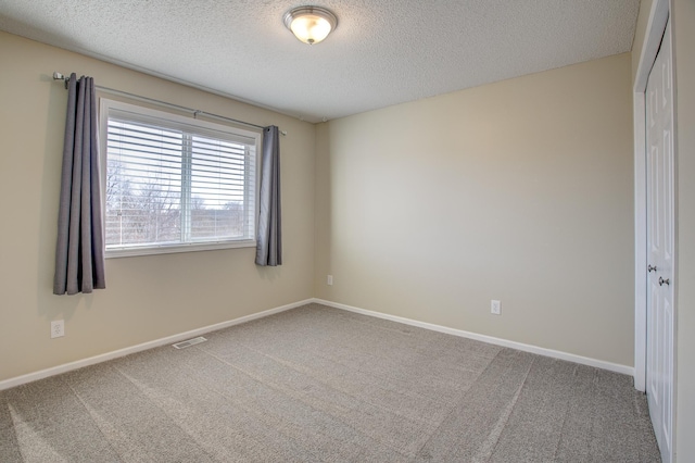 unfurnished room with carpet flooring and a textured ceiling