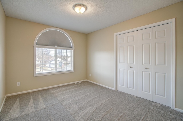 unfurnished bedroom with a closet, a textured ceiling, and carpet