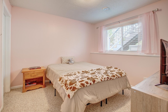 bedroom with light colored carpet and a textured ceiling