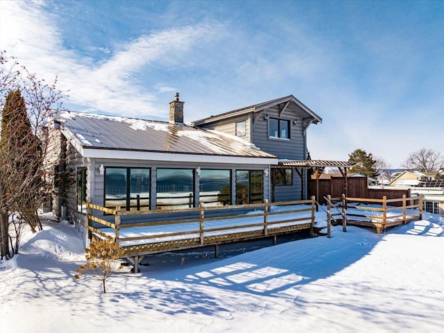 snow covered property featuring metal roof and a chimney