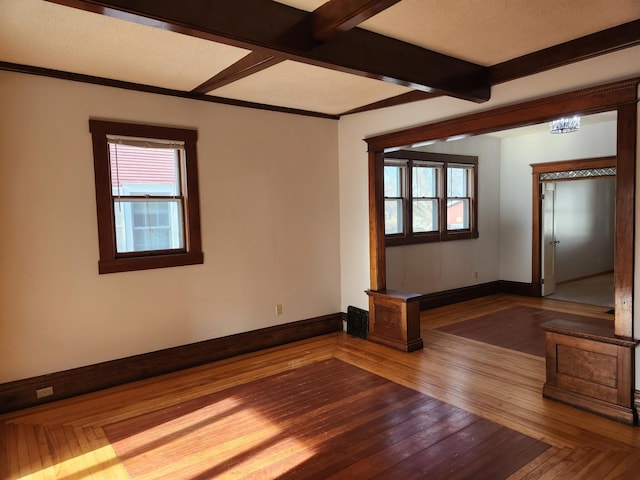 empty room featuring plenty of natural light, beamed ceiling, and hardwood / wood-style flooring