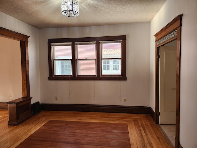 interior space with hardwood / wood-style floors, a textured ceiling, and a notable chandelier