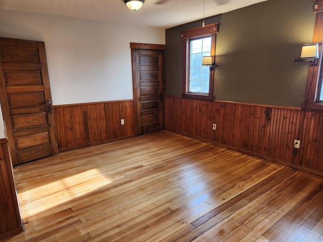 spare room with ceiling fan, a textured ceiling, and light hardwood / wood-style flooring