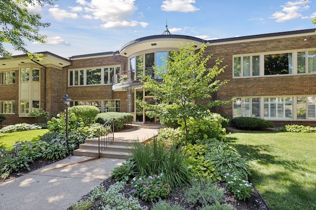 view of front facade with a balcony and a front yard