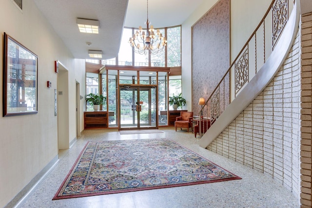 foyer with plenty of natural light, a high ceiling, french doors, and a notable chandelier