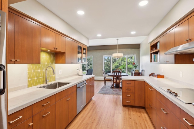 kitchen featuring stainless steel dishwasher, white gas stovetop, sink, decorative light fixtures, and light hardwood / wood-style floors