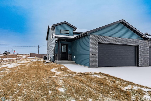 view of front of property featuring a garage and cooling unit