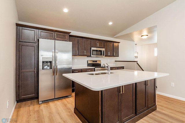 kitchen featuring appliances with stainless steel finishes, a kitchen island with sink, lofted ceiling, dark brown cabinets, and sink